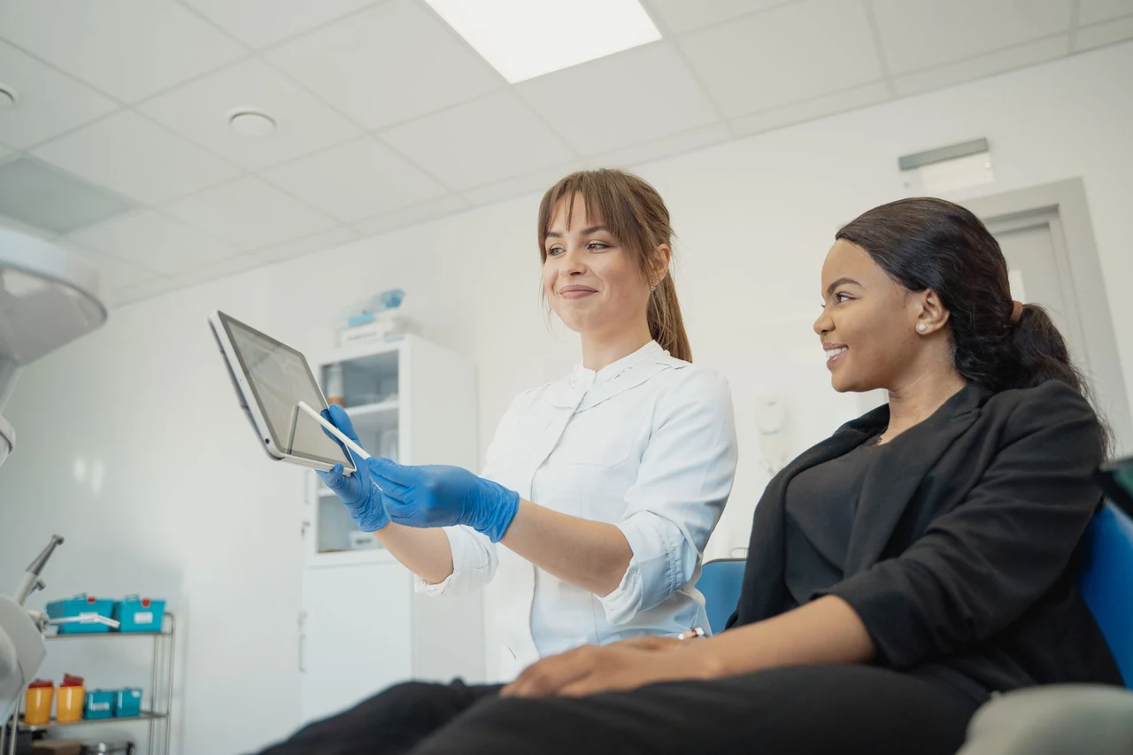 Two people discussing information on a tablet in a dental setting.