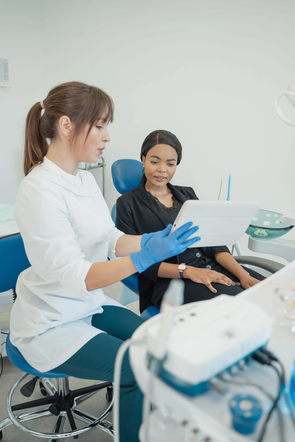 Two people seated in a dental consultation, looking at a tablet.